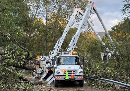 Two bucket trucks clear debris after Hurrican Helene