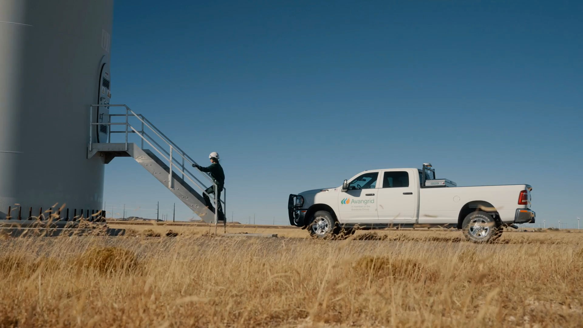 An Avangrid truck and worker at a wind turbine.